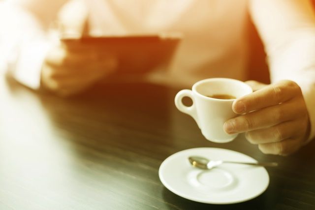 エスプレッソが入ったカップを持ち上げている