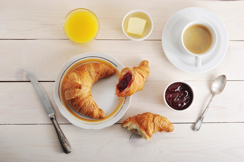 テーブルに並べられたクロワッサン、コーヒー、ジャム、バター