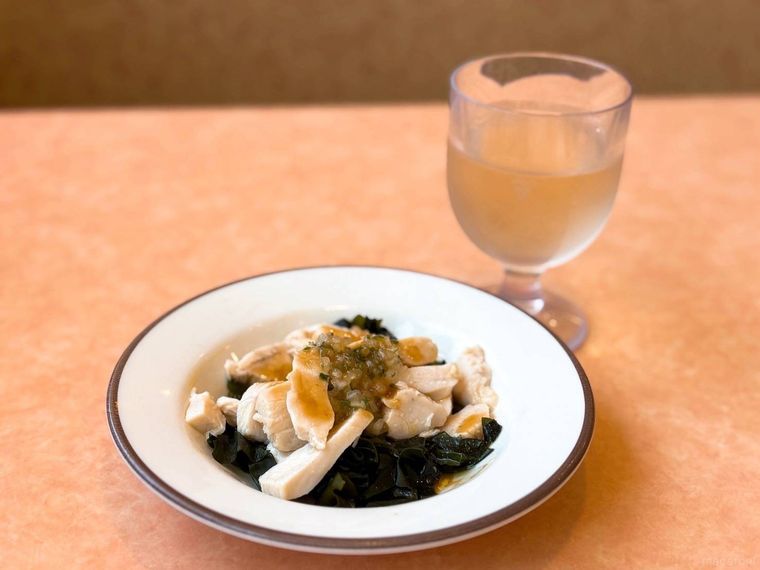 鶏肉のサラダと白ワインが机に並ぶ