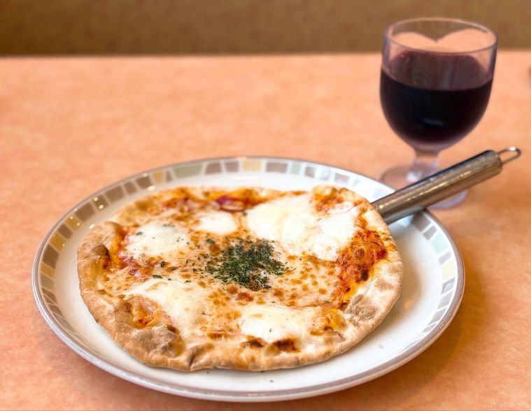 ピザと赤ワインのグラスが机に並ぶ