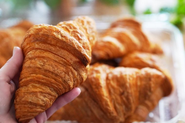 数個のクロワッサンと手で持ち上げたクロワッサン