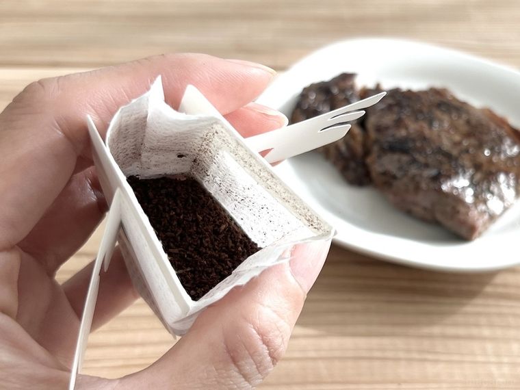 更に盛り付けたステーキと手に持ったドリップコーヒー