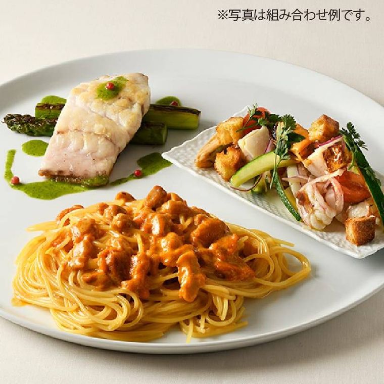 おさらの上にパスタと前菜、魚料理がのって置いてある