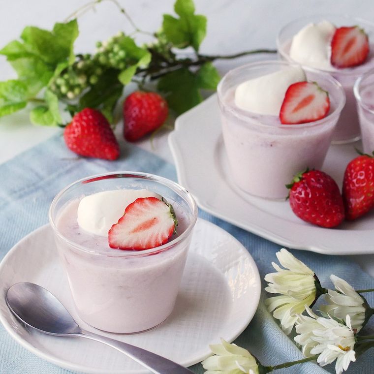 グラスに盛り付けられたいちごの牛乳プリンにいちごと生クリームがトッピングされている