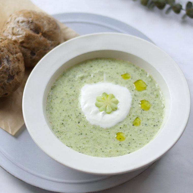 白いお皿の上にスープ皿に入った枝豆ポタージュとパンがのっている