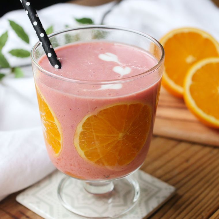 グラスの側面にオレンジを張り付けたピンク色のスムージー