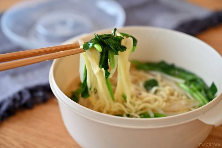 白い容器に入ったインスタントラーメンを箸でつまみあげている