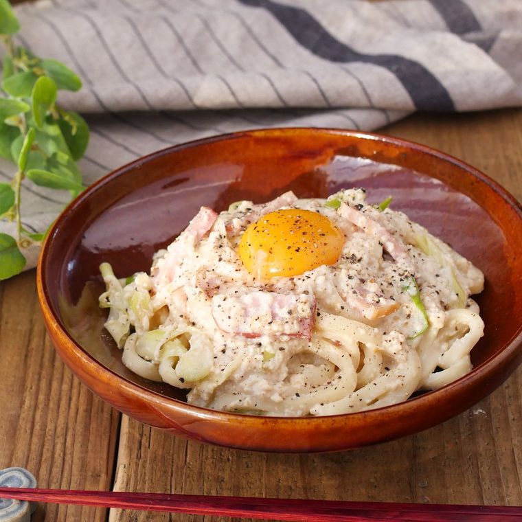 茶色い皿に盛られた和風カルボナーラうどん