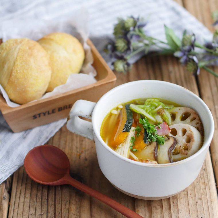 スープカップに盛られた焼き野菜とベーコンのスープと、皿にのったパン