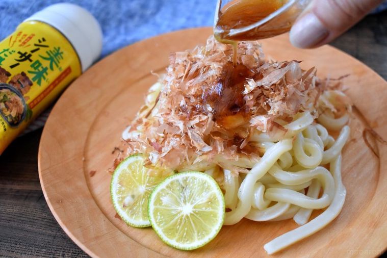 かつおぶしをのせたうどんに美味シーサーだれをかけているところ