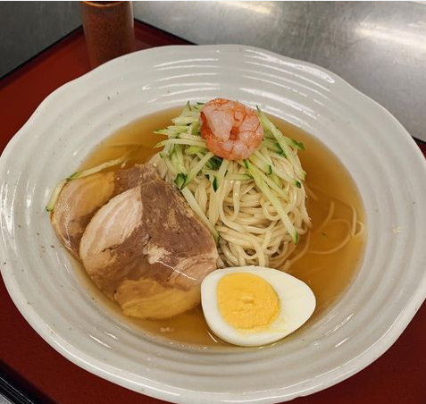 白く丸い器に盛られた呉冷麺。トッピングはエビ、キュウリ、ゆでなど玉子