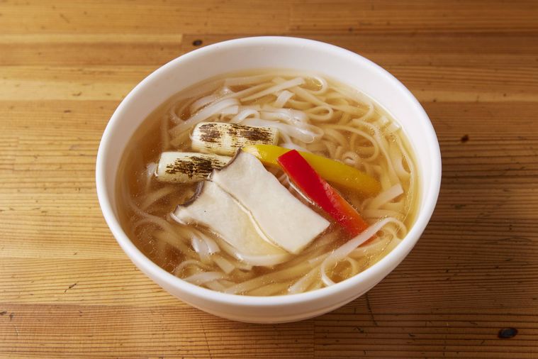 どんぶりの中にネギやパプリカがのったラーメンが入って置いてある