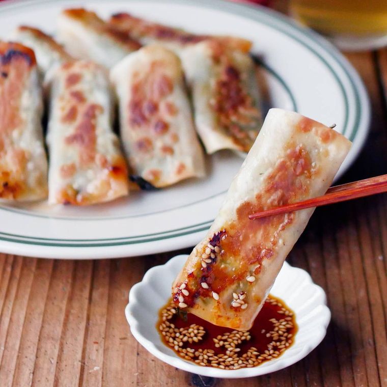 豚キムチ棒餃子を白い小皿に入ったたれに付けている様子