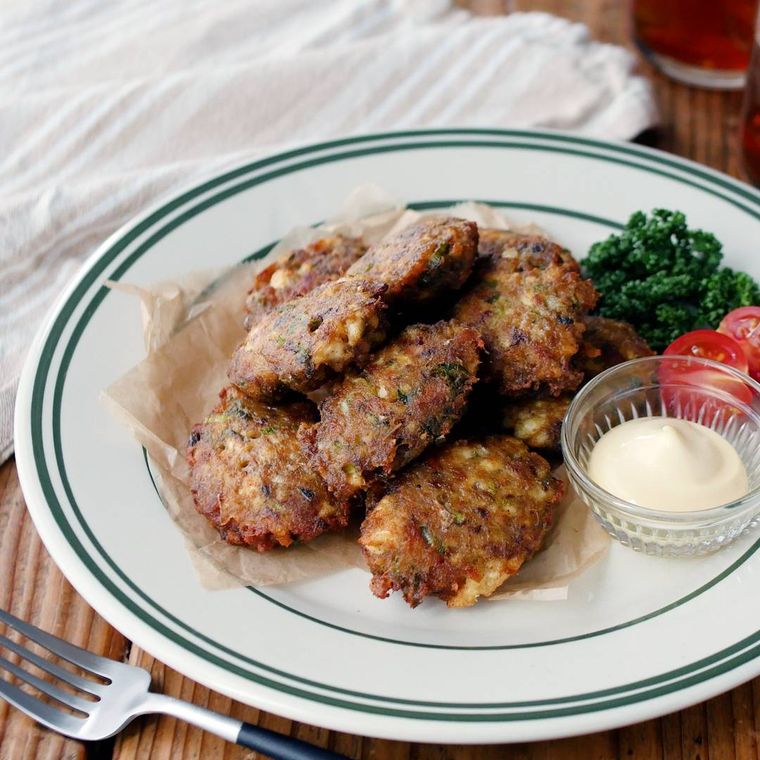 緑の線が入った白い皿に盛り付けられたさばと豆腐のナゲット