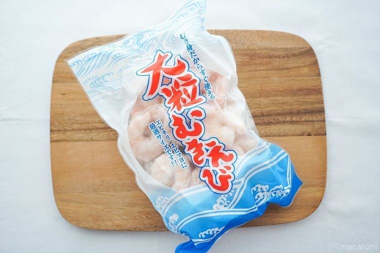 木のまな板にのせた冷凍大粒むきえびのパッケージ