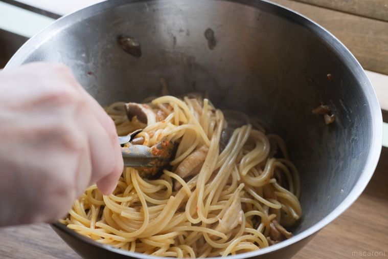 ボウルに入れたパスタと具材、調味料をトングで合わせる様子