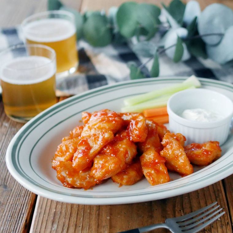 オーバル皿に鶏むね肉のバッファローチキン風とサワークリーム、セロリ、にんじんがのっている