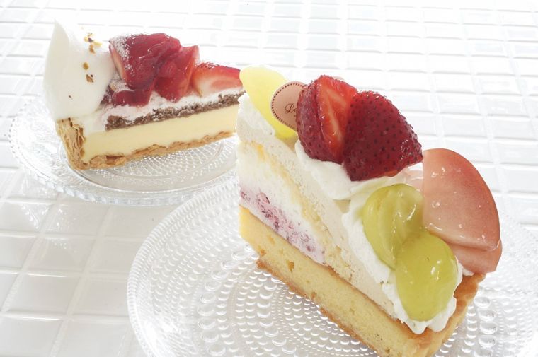 ガラスの皿に盛り付けられたいちごのタルトとシャインマスカットといちごのミルクティータルト