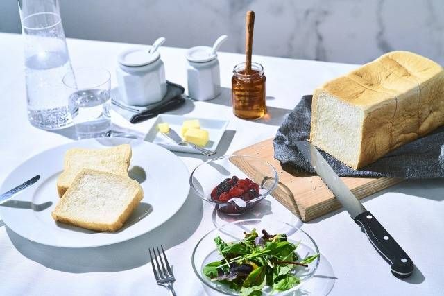 テーブルの上に食パンやサラダ、バターなどが置いてある