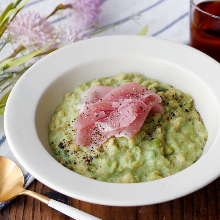 白い皿に盛り付けられ、生ハムを添えたアボカドチーズリゾット