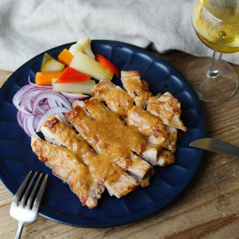 濃い青色のお皿に甘酒みそチキンソテーが盛り付けられている