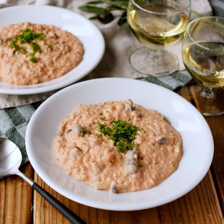 木の机の上に、白い丸皿に盛られたオートミールのトマトクリームリゾットが置かれている