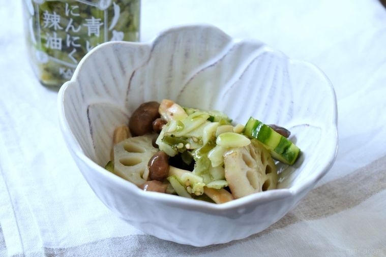 小鉢に入れた青いにんにく辣油と野菜の和えもの、青いにんにく辣油のボトル