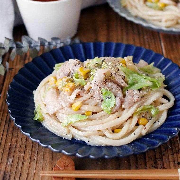 紺色の皿に盛り付けられた豚肉とキャベツのごまみそうどん