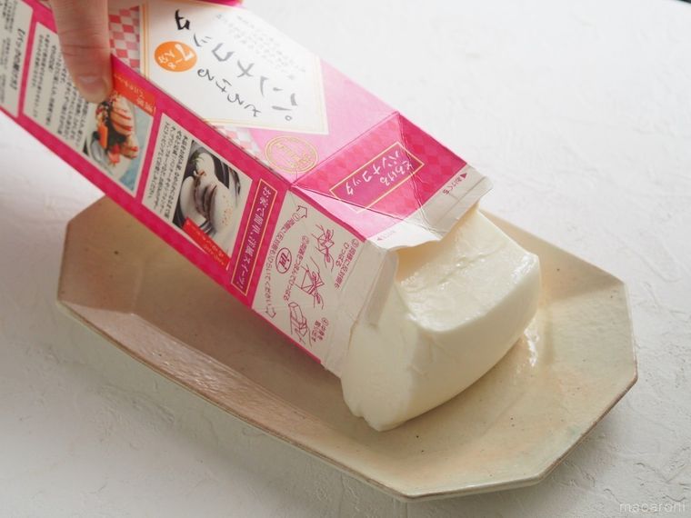 業務スーパーのパンナコッタが入ったパックを皿に向かって傾ける様子