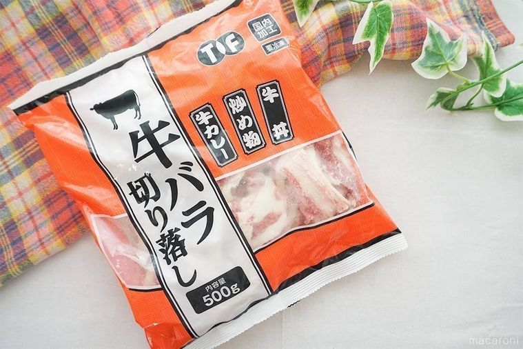 牛バラ切り落としのパッケージをテーブルに置き、緑の葉とチェック柄の布を添えた様子