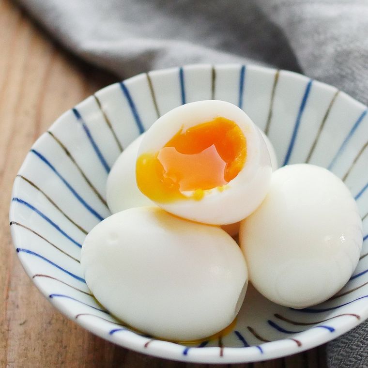 縞模様の器にゆで卵が4個置かれ、そのうちのひとつは半分にカットされている