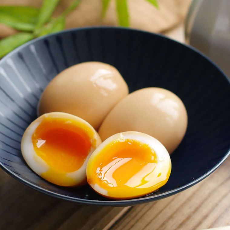 黒い浅鉢に煮卵が3個入っており、そのうちの1個は半分にカットされている