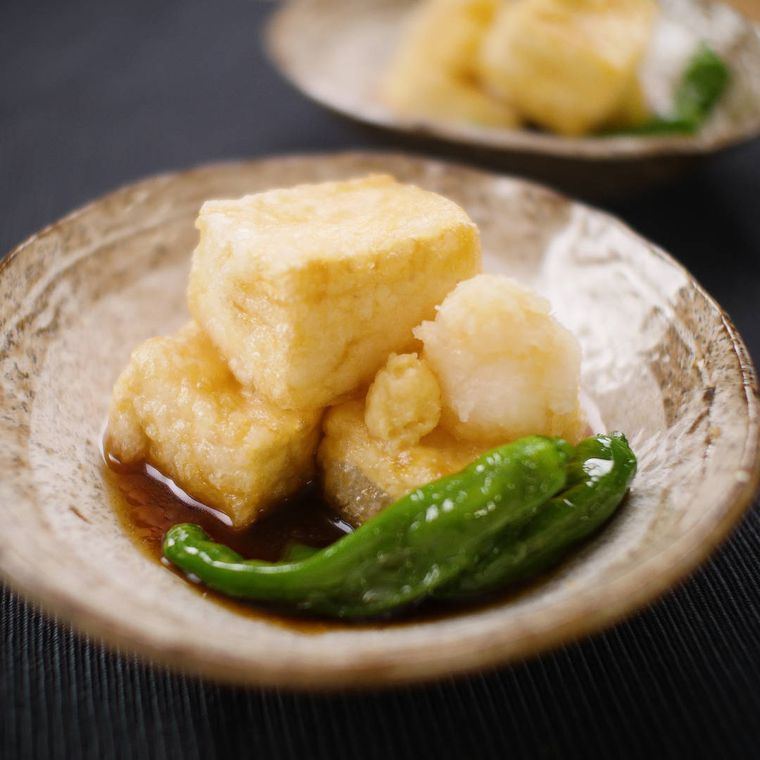 茶色い和皿に盛った揚げ出し豆腐とししとうがらし