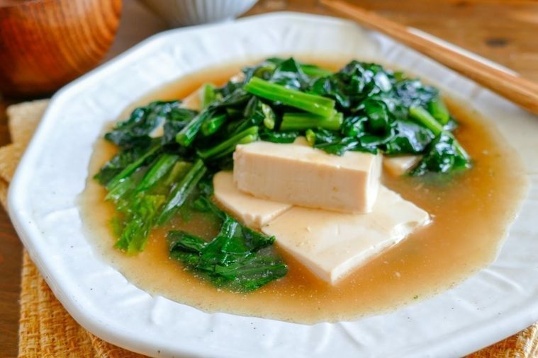 白い皿に盛り付けられたほうれん草と豆腐のあんかけ煮