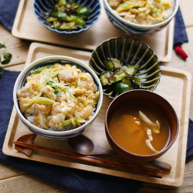 木のトレーの上に、丼茶碗に盛られた親子丼と、味噌汁と、小鉢に盛られたきゅうりの塩昆布和えがのっている
