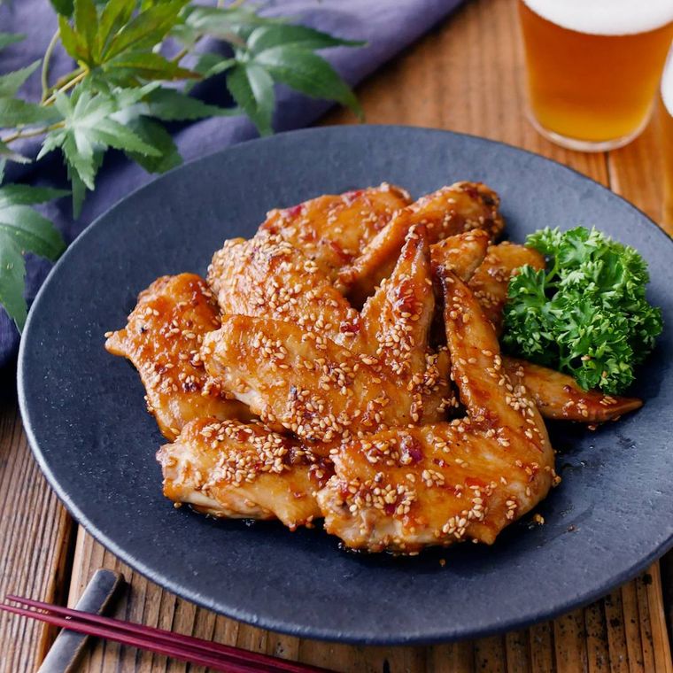 黒い丸皿に盛り付けた鶏手羽先の照り焼き