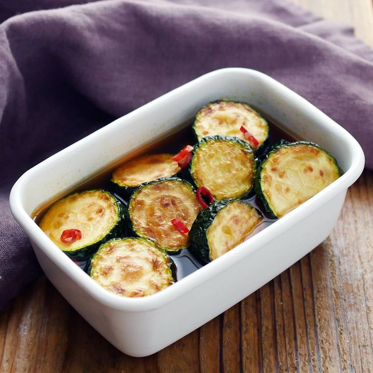 白い長方形の容器に入っているズッキーニの揚げ浸し