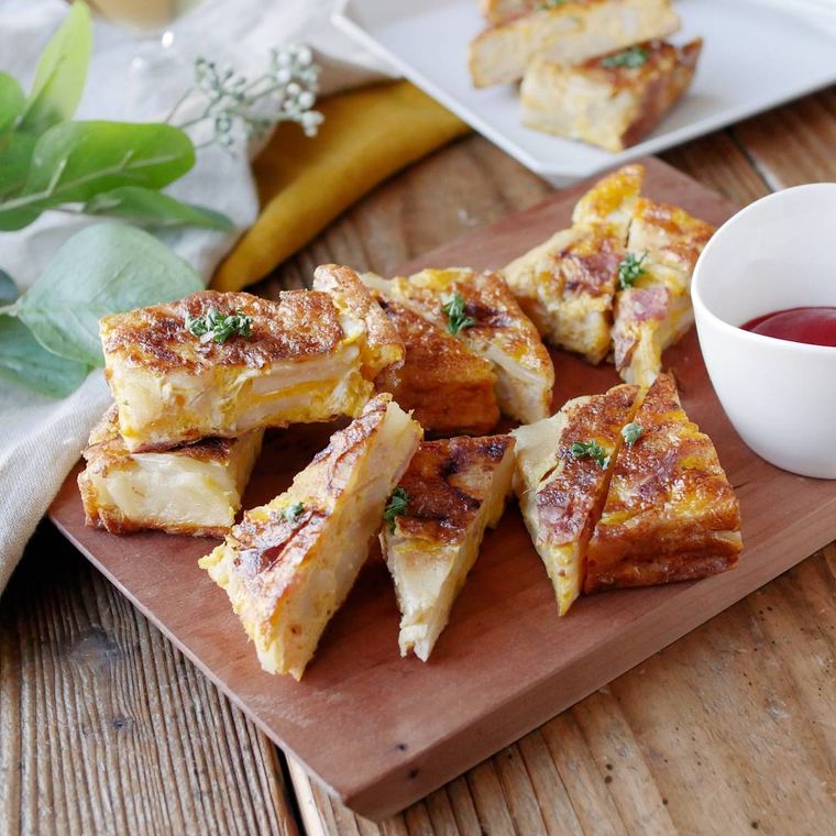 カッティングボードに盛られたじゃがいもとベーコンのチーズオムレツ