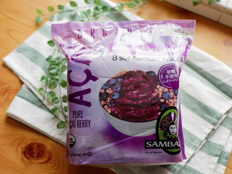 木のテーブルにのったコストコのサンバゾンアサイー、グリーンと白のストライプキッチンクロス