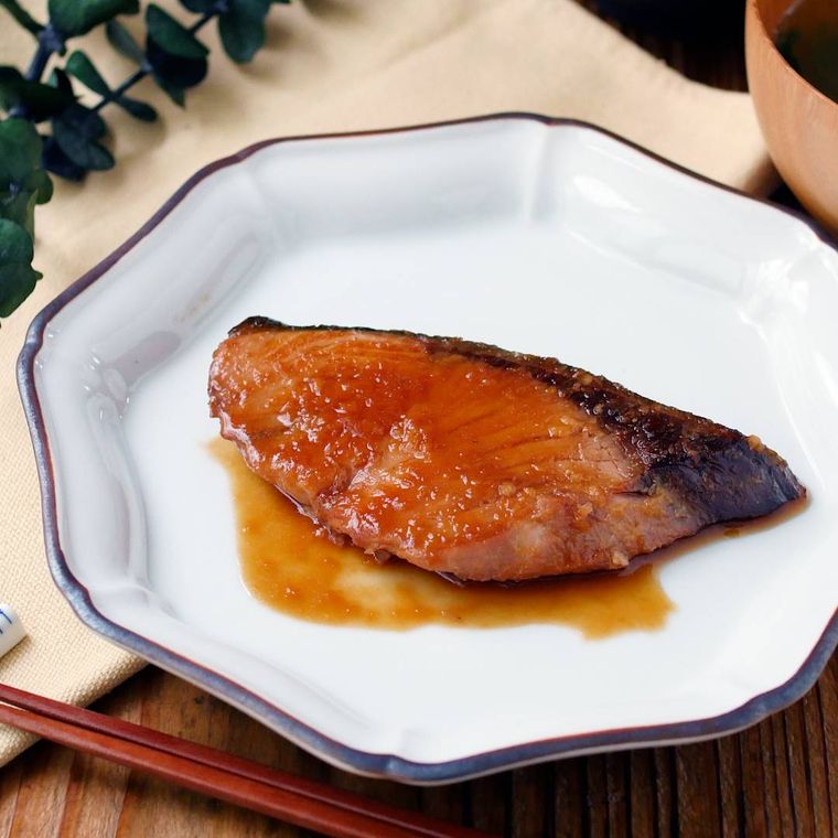 グレーに縁取りされた白い皿に盛られたぶりのしょうが焼き