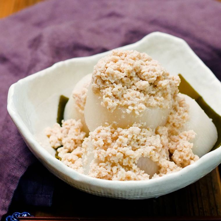 紫の布の上にのせた白い角皿に、昆布を敷き大根を盛って、肉みそだれをかけた様子