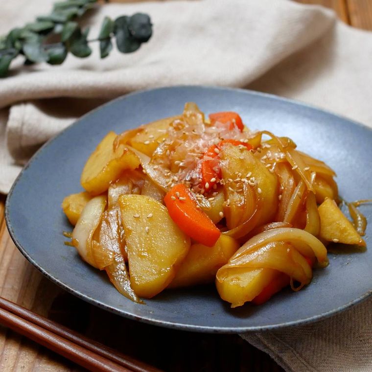 黒色のお皿に盛られたにんじんとじゃがいもと玉ねぎの甘辛炒め