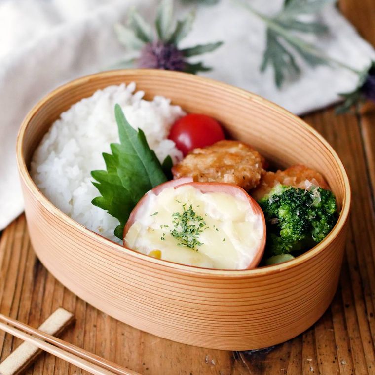 わっぱの弁当箱に、ごはん、大葉、ハムカップのグラタン、つくね、ミニトマト、ブロッコリーなどが詰め込まれている