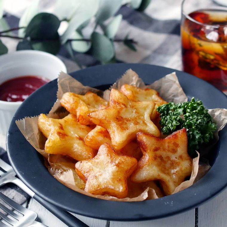 紺色の皿に、星型のハッシュドポテトが盛られ、その奥にはケチャップが入った容器と、お茶が入ったグラスが置かれている