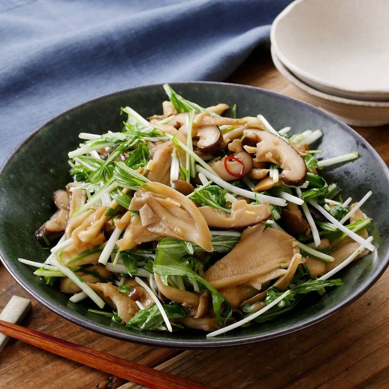 シンプルな黒い器に盛り付けられているきのこと水菜のホットサラダ