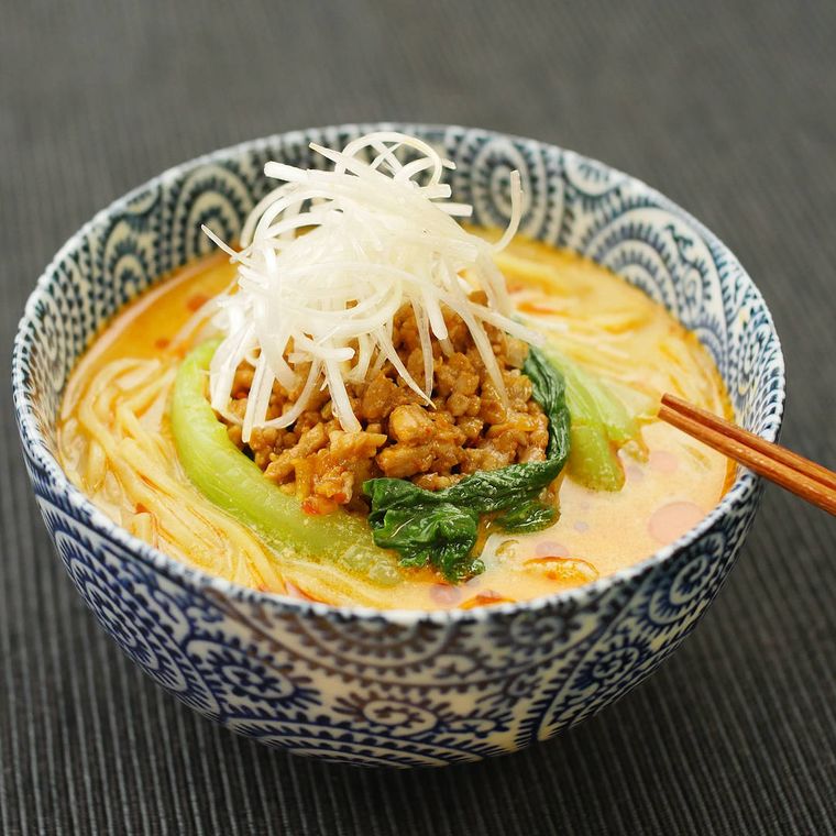 担々麺が盛られた藍草紋の丼が、黒いテーブルの上に置かれている