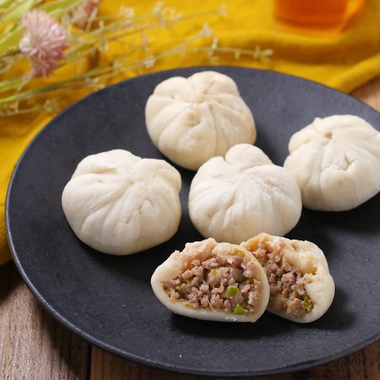 食パンで作られた肉まんが5個、黒い丸皿の上に並べられており、そのうちの1個は半分に割られて中の具材が見えている