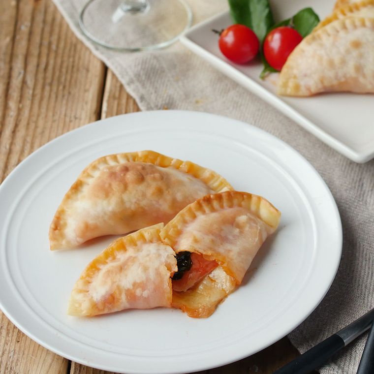 小さなカルツォーネが2つ並ぶ皿が置かれているテーブル