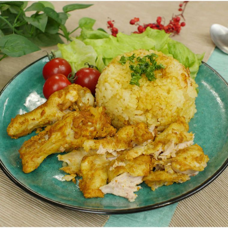 青い丸皿に盛り付けられたタンドリーチキンライス・レタス・ミニトマト3個と、奥にスプーンが置かれている