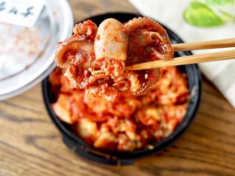 「沈菜館 イイダコの海鮮キムチ」を箸で持ち上げた様子